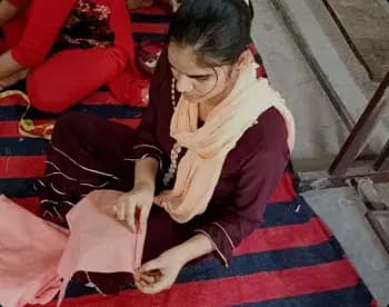 A young woman stitching fabric at a Ramagya Foundation skill development session